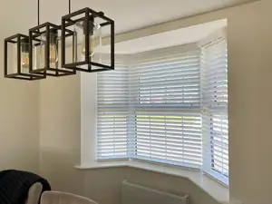 White wooden venetian blinds in a bay window