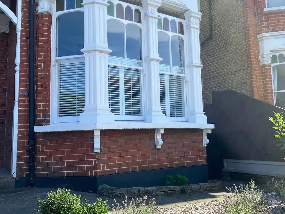 Cafe-style shutters seen from the street in a red-brick Victorian bay