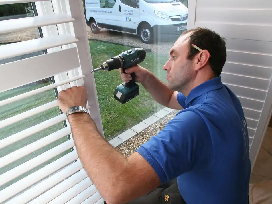 One of our own fitters installing shutters, with the Lifestyle van outside